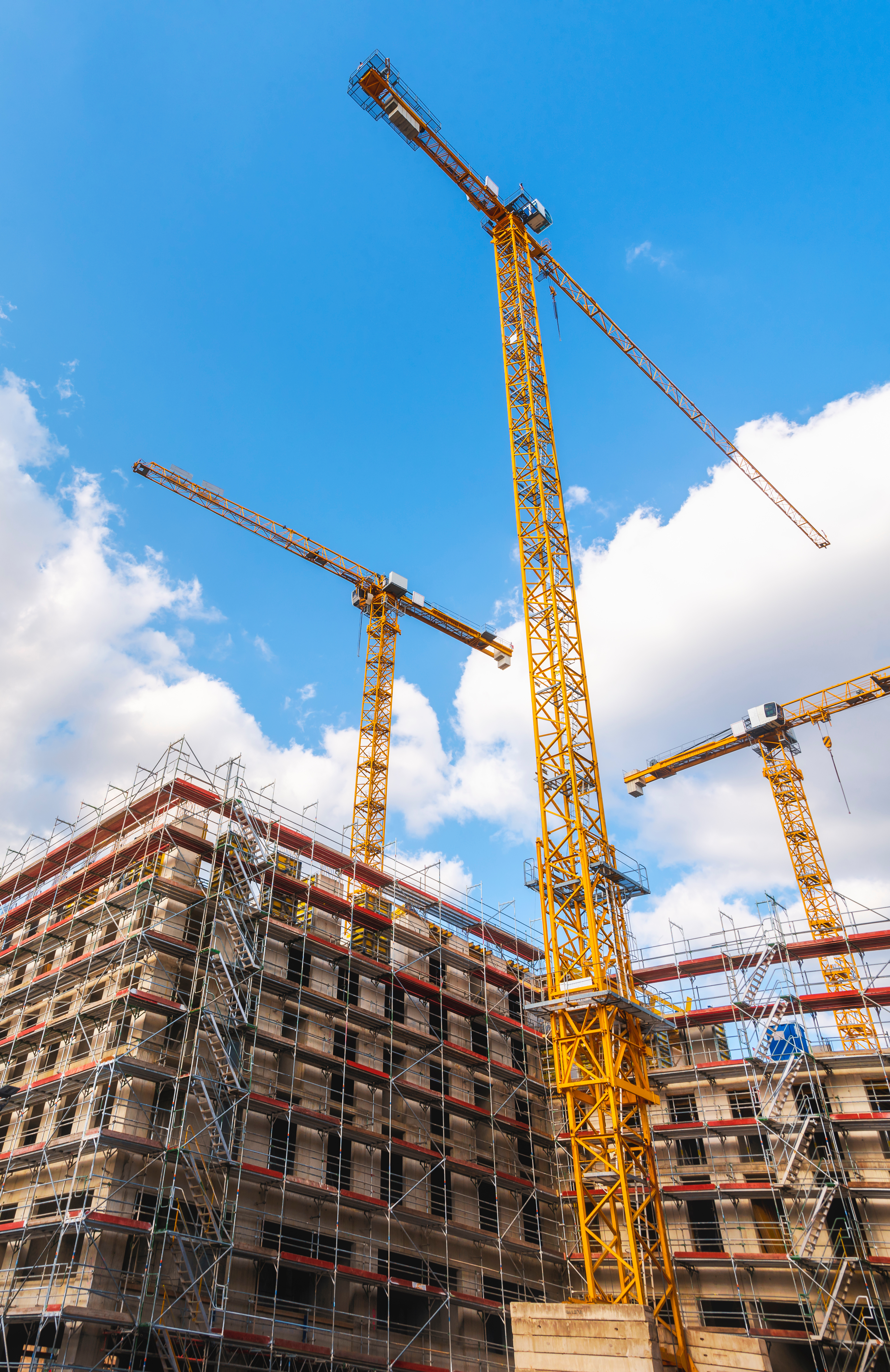 Construction site with yellow cranes and metal structure, on a sunny day, in Stuttgart, Germany. Unfinished building with no people.