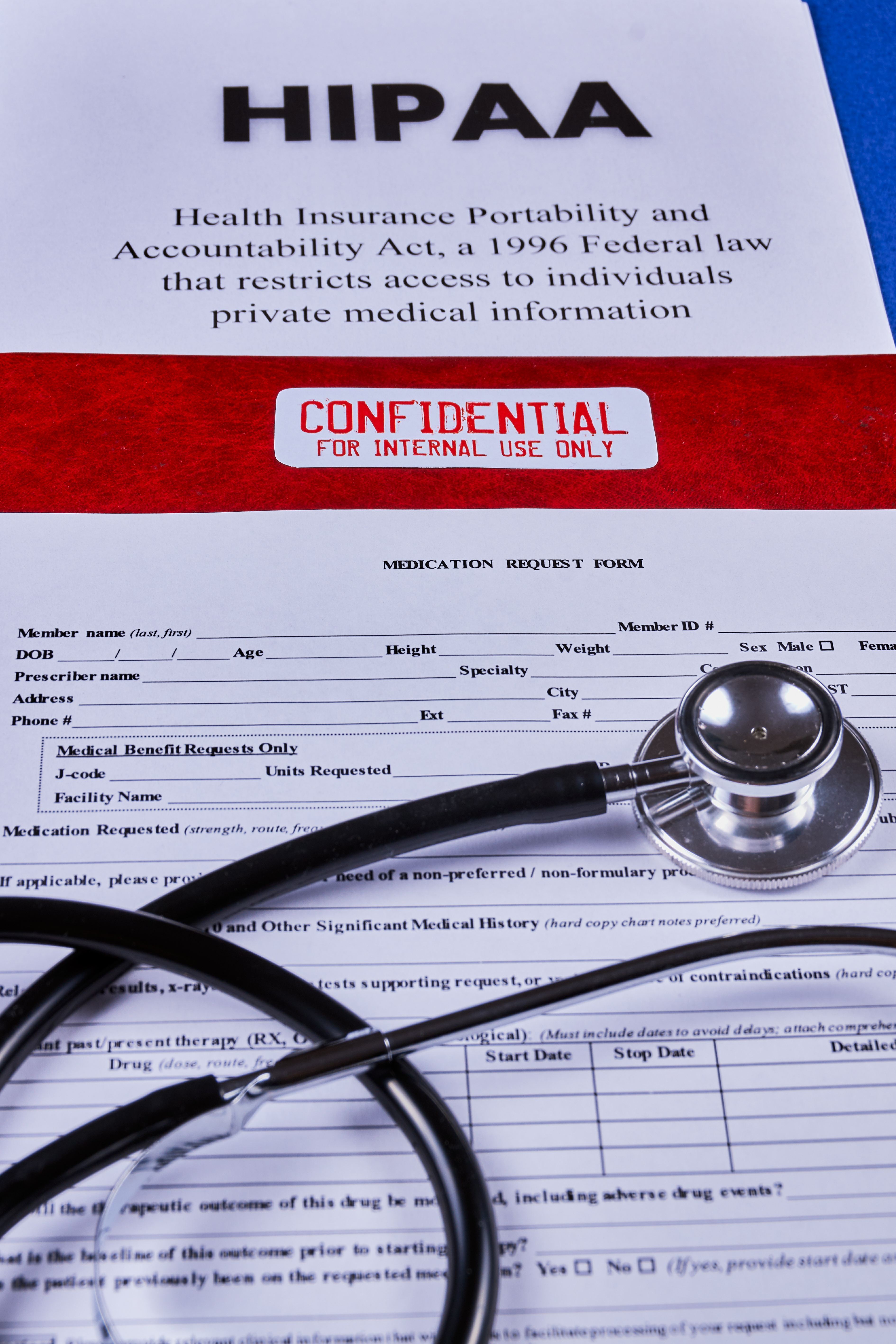 Health Insurance Portability and accountability act HIPAA, red folder with inscription confidential, medication request form and stethoscope on a blue velvet background. Close-up